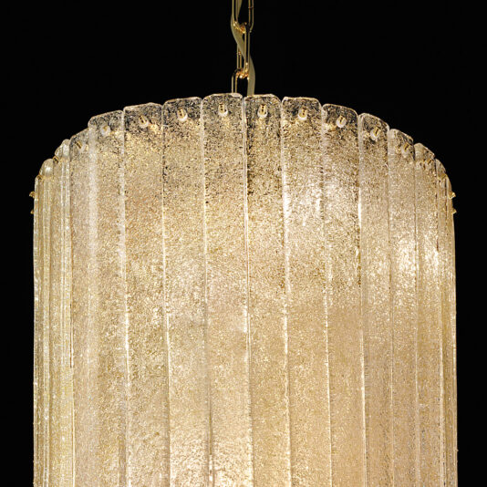 A detailed view of the Luxury Tiered Amber Glass Chandelier reveals vertically aligned amber glass panels, suspended gracefully from a gold chain. The frosted, textured panels softly diffuse light against a black backdrop, accentuating the chandelier's luminous elegance.