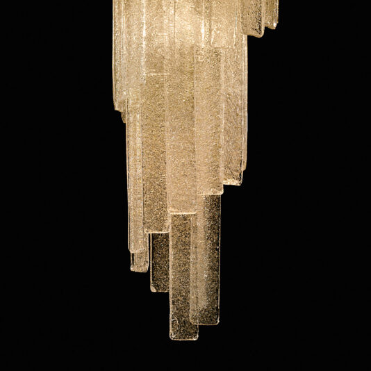 A close-up view of the Luxury Tiered Amber Glass Chandelier, showcasing its cascading amber glass panels. The chandelier is illuminated, emitting a warm, ambient light against a black background.