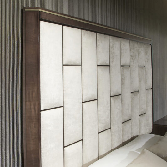 Luxury Velvet Fabric Upholstered Bed The Luxury Velvet Fabric Upholstered Bed boasts a large, modern headboard with a geometric, padded design featuring rectangular panels of light gray velvet upholstery framed with dark wood. Set against a wall with a textured finish, this bed creates a sophisticated and stylish bedroom aesthetic.