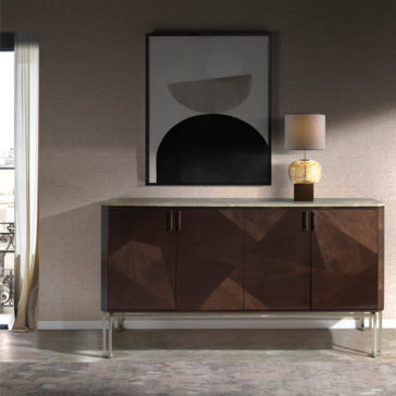 The Marble Top Brown Maple Sideboard, featuring a modern geometric wood pattern and a sleek marble top brown maple finish, stands against a textured wall. Atop the sideboard sits a decorative lamp with a patterned base, while a minimalist black and white abstract painting is hung above it. Natural light streams in from a nearby window.