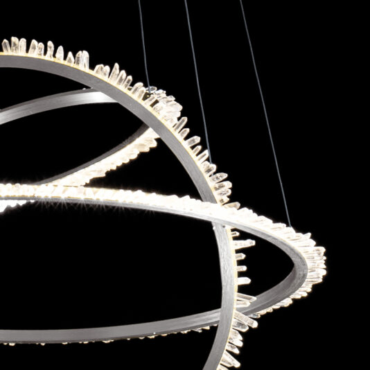 Modern Nickel Quartz Crystal Hoop Chandelier The Modern Nickel Quartz Crystal Hoop Chandelier features interlocking rings adorned with small LED lights, creating a dynamic and elegant design against a black background. The lights emit a soft, bright glow, highlighting the intricate details and the metallic finish of the structure.