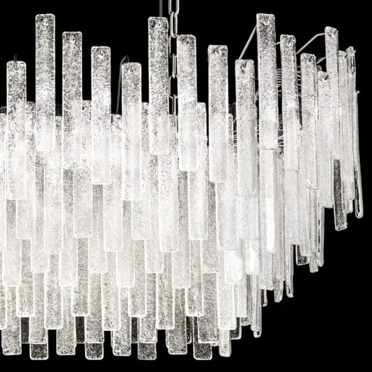 Modern Oval Glass Chandelier A detailed look at the Modern Oval Glass Chandelier reveals its sophisticated rectangular design adorned with numerous hanging glass rods that boast a textured, frosted finish. These glass rods are meticulously arranged in multiple layers, creating a stunning cascading effect that beautifully reflects light against a black backdrop.