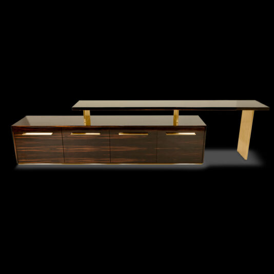 Modern Veneered TV Unit The Modern Veneered TV Unit showcases a sleek design with dark wooden panels and gold handles. It features a rectangular base unit with multiple drawers and an elevated top surface supported by elegant gold stands, all set against a solid black background.