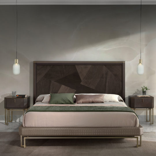 A modern bedroom features an Opulent Brown Maple Veneer Bed headboard, a large bed adorned with green and beige bedding, and two matching nightstands with brass legs. Pendant lights illuminate the nightstands from above, while a neutral-toned rug partially covers the wooden floor.