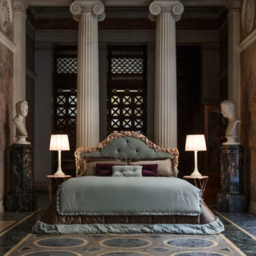 Ornate Classic Style Button Upholstered Bed A luxurious bedroom showcasing the Ornate Classic Style Button Upholstered Bed, covered in elegant light blue bedding and flanked by two bedside tables with white lamps. The room features classic elements like columns and marble busts on pedestals, creating a grand aesthetic.