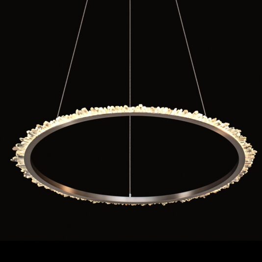 The Small Quartz Crystal Nickel Round Chandelier features a contemporary nickel design with a sleek metal ring frame, accented by a textured edge of small quartz crystals. Suspended by thin wires against a black backdrop, the light from this fixture illuminates the crystals to create a glowing effect.