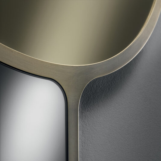 Close-up of the Modern Designer Curved Bronze Wall Mirror, exhibiting its sleek and elegant design. The image highlights a smooth, brushed metal frame that transitions seamlessly into reflective glass surfaces and textured gray material. The design features clean lines and a minimalist aesthetic.