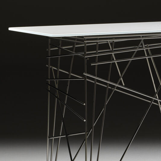 The Contemporary Lacquered Console Table, with its sleek white rectangular top, is paired beautifully with an intricate metal wireframe base. Set against a dark background, the metal base features a stunning geometric design of intersecting lines and angles.
