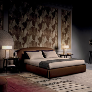 Contemporary Leather Upholstered Curved Bed A contemporary bedroom features a Contemporary Leather Upholstered Curved Bed with neutral bedding and a dark gray throw blanket. Two matching nightstands with sleek table lamps flank the bed, while the wall behind it is adorned with large leaf-patterned panels.