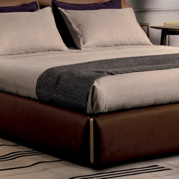 Contemporary Leather Upholstered Curved Bed The modern bedroom is dominated by the Contemporary Leather Upholstered Curved Bed, neatly made with beige linens and dark gray accents. Pillow shams perfectly match the beige linens, while a textured gray throw is elegantly laid across the foot of the bed. Adjacent to it, a wooden nightstand holds a framed picture and table lamp.