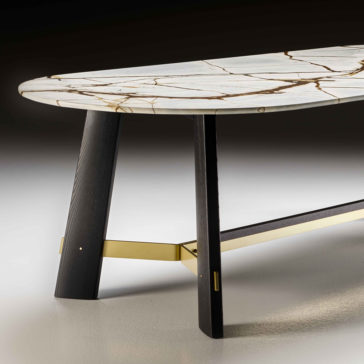 The Contemporary Oval Quartz Dining Table features a stylish marbled white and brown oval top, supported by three dark wooden legs and connected by gold-toned metal braces. Its contemporary and elegant design emphasizes the contrast between the light tabletop and dark legs, making it perfect for any modern home.