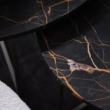 Contemporary Round Marble Coffee Table Set A close-up view of a dark marble surface with intricate golden-orange veins against a black background forming a striking natural pattern. The polished edges and shadows suggest the Contemporary Round Marble Coffee Table Set, with a white textured object partially visible in the corner.