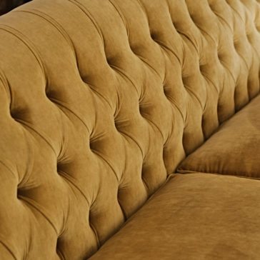 Large Button Upholstered Velvet Sofa Close-up of the Large Button Upholstered Velvet Sofa, showcasing the intricate texture of its button-tufted design on the backrest and a portion of the plush, smooth cushion seat in a rich tan hue.