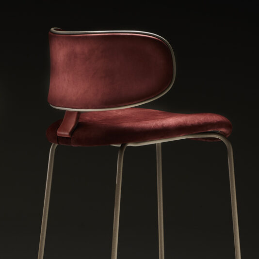 Luxury Mid Century Style Bar Stool The Luxury Mid Century Style Bar Stool boasts a sleek, modern design with a burgundy velvet seat and backrest, both elegantly framed with metallic trim. Its thin metal legs complement the overall aesthetic, creating a striking contrast against a black background that highlights its elegant design and luxurious finish.