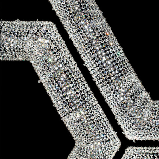 Luxury Octagonal Crystal Pendant Chandelier Close-up of two intersecting, angled metal beams adorned with glistening silver rhinestones, resembling the Luxury Octagonal Crystal Pendant Chandelier, against a black background for a sparkling, luxurious effect.