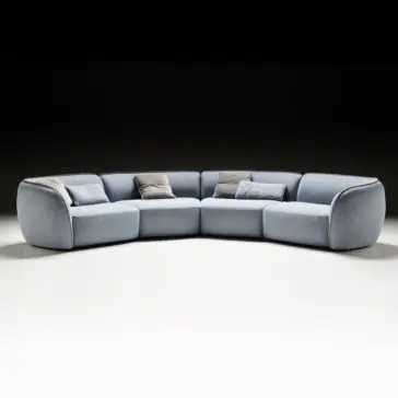 Modern Bouclè Modular Corner Sofa The Modern Bouclè Modular Corner Sofa, featuring a light blue hue and rounded edges, is elegantly placed against a black backdrop. This L-shaped sectional comes with grey and beige accent pillows, presenting a contemporary and cozy look ideal for a spacious living room.