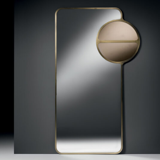 The Modern Designer Curved Bronze Wall Mirror is set against a dark background, featuring a unique design in the upper right corner: a circular section divided horizontally, with the top half in beige and the bottom half in a reflective surface.