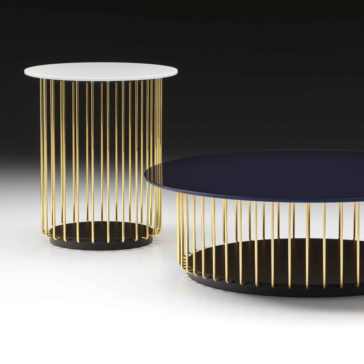 Contemporary Round Glass Coffee Table Two contemporary round tables with thin gold vertical rods as the base. One table has a white top and is taller, while the other has a black top and is shorter. Both tables are placed on a sleek black and white surface. The elegant design of these Contemporary Round Glass Coffee Tables rivals any modern glass coffee table.