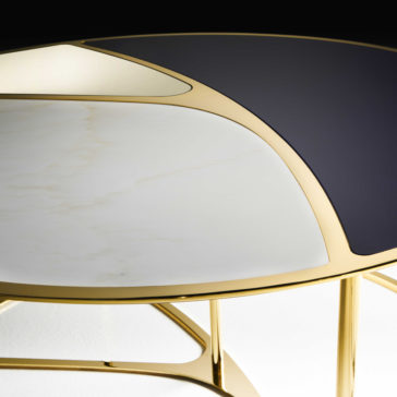 A close-up view of the Modern Nest Of Coffee Tables, showcasing a stylish and sleek design with a gold metallic frame. The tabletop is composed of three distinct sections: a black panel, a white marble panel, and a light beige panel, all arranged in an elegant geometric pattern.