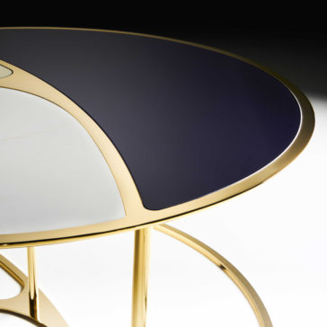 The Modern Nest Of Coffee Tables boasts a sleek, contemporary design featuring a round shape with a shiny gold frame and a divided top in sections of black and white, embodying a minimalist aesthetic.