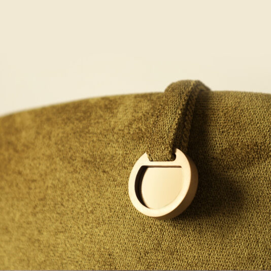 Modern Swivel Tub Chair Close-up of a green textured bag with a metal ring attachment. The horseshoe-shaped ring, reminiscent of the sleek curve of the Modern Swivel Tub Chair, is partially embedded in a matching fabric loop on the bag's surface, set against a neutral background.