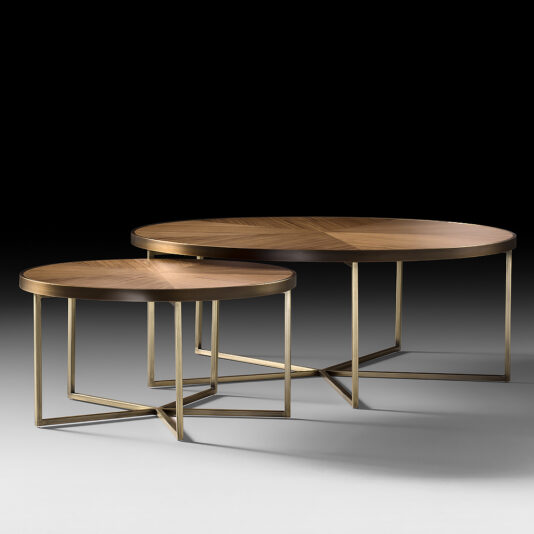 The Round Walnut Veneer Coffee Table Set includes two modern nesting tables with round walnut veneer tops and gold metal frames. The larger table is positioned slightly behind and to the right of the smaller one, both showcasing geometric base designs and resting on a smooth, gradient background.