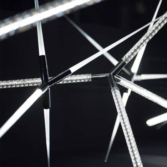 Luxury Crystal LED Chandelier A close-up of a Luxury Crystal LED Chandelier showcases its modern, abstract design composed of intersecting metallic rods with embedded LED lights, creating a web-like pattern against a dark background. The chandelier casts a cool, white glow, highlighting its sleek, geometric elegance.