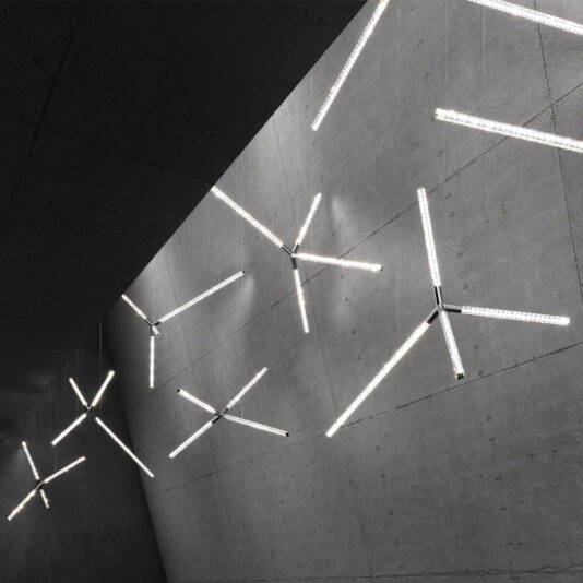 A sophisticated ceiling adorned with the Luxury Crystal LED Chandelier, featuring an innovative cross-shaped design and suspended from a concrete ceiling. The lights are strategically positioned at various angles, creating a stunning artistic and contemporary ambiance.