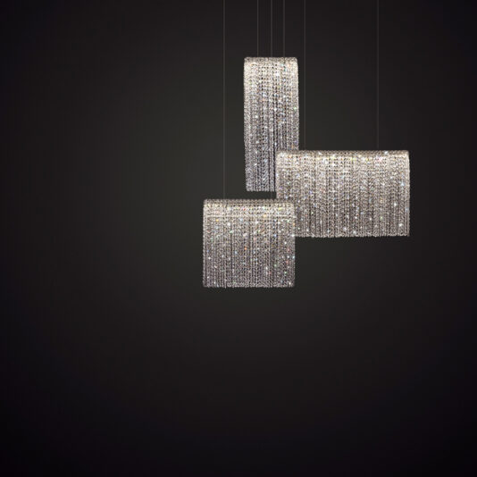 A photograph of three Luxury Narrow Cut Crystal Chandeliers hanging from thin wires against a dark background. The crystal strands dangle from each chandelier, creating a luxurious and sophisticated lighting fixture.