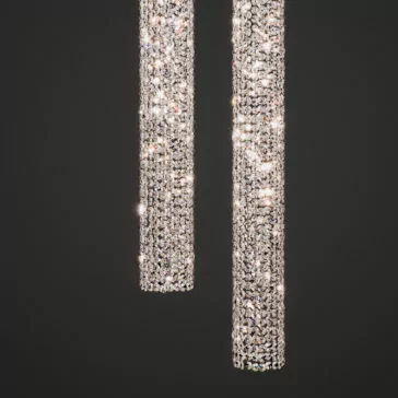 Luxury Vertical Crystal LED Chandelier Two cylindrical Luxury Vertical Crystal LED Chandeliers suspended against a black backdrop, showcasing their numerous sparkling crystals that create a dazzling and elegant light display. The crystals catch and reflect light magnificently, enhancing their shimmer and brilliance.