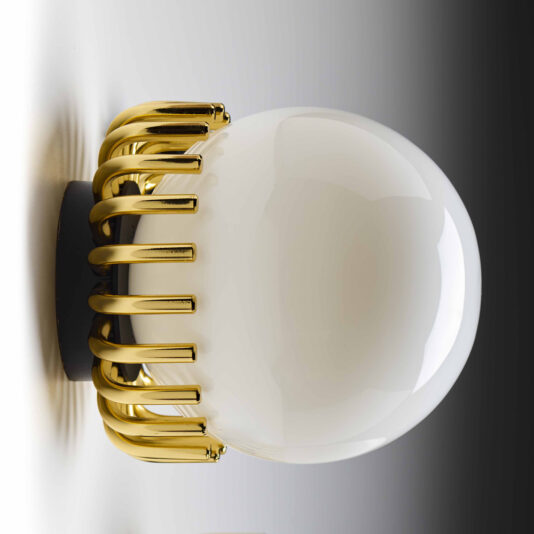 Small Contemporary Sphere Wall Light The Small Contemporary Sphere Wall Light showcases a white spherical bulb with a modern, elegant design, partially encased in a gold metallic frame. Evenly spaced bars wrap around the bottom half of the light, set against a backdrop that shifts from bright on the left to dark on the right, producing a striking gradient effect.