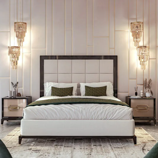 Art Deco Style Bed With Tall Headboard In a modern bedroom, an Art Deco Style Bed with a tall, beige upholstered headboard takes center stage, complemented by white bedding and two green accent pillows. Flanking the bed are two sleek nightstands with golden handles, each crowned with a decorative lamp. Vertical lighting fixtures enhance the aesthetic of the walls.