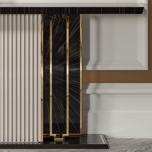 A close-up of the Art Deco Style Veneer Console Table leg showcases glossy black vertical panels adorned with intricate gold lines forming a starburst pattern, accompanied by adjacent white panels featuring a ribbed texture. The background highlights a white wall with elegant molding and a beige section.