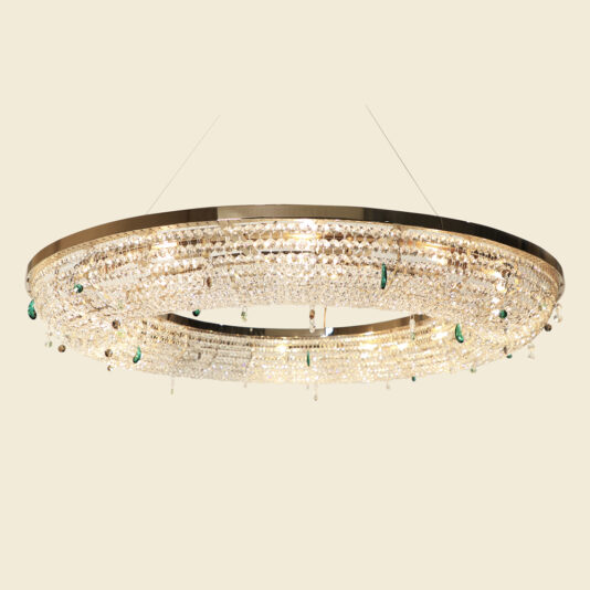 The Contemporary Crystal Chandelier With Coloured Drops boasts a sleek metal frame adorned with numerous clear and green crystals. This large, circular chandelier emits a warm, elegant glow and is suspended from the ceiling by thin wires against a neutral background.