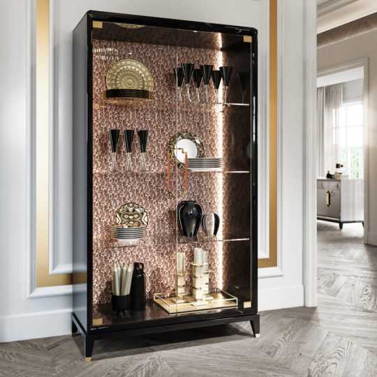The High End Glass Display Cabinet, adorned with black and gold accents, is elegantly filled with exquisite glassware, dishes, vases, and decorative items. Featuring glass shelves, the cabinet is set against a wall with gold trim, enhancing the luxurious ambiance of the room.