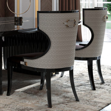 Luxury Art Deco Style Veneer Dining Set A dining room scene showcasing two elegant Bristol high-back chairs, upholstered in a textured gray fabric and featuring sleek black wooden frames. The Bristol chairs are placed around the Luxury Art Deco Style Veneer Dining Setās glossy black dining table with a polished glass top, exuding an air of sophistication. Tall windows with rich brown curtains allow natural light to flood the room, completing the stunning ensemble.