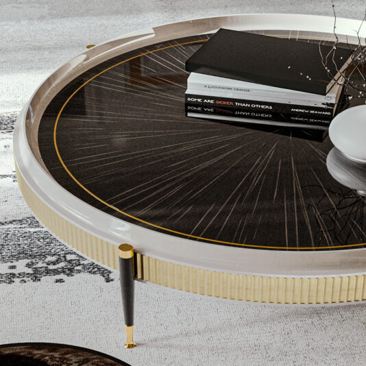 High End Veneered Low Round Coffee Table The High End Veneered Low Round Coffee Table, featuring a dark glass top with a stunning sunburst design and elegant gold accents, is adorned with several books and a modern vase filled with branches. The room exudes style with its light-colored rug and contemporary decor.