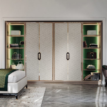 Large High End Integrated Wardrobe A modern bedroom showcases the Large High End Integrated Wardrobe, complete with intricate geometric-patterned sliding doors. Flanked by open shelves displaying folded clothes, bags, and accessories, this stylish wardrobe complements the neatly made bed adorned with green bedding and a decorative rug.