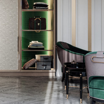 Large High End Integrated Wardrobe A luxurious interior features a minimalist black table, elegant chairs with green cushions and metallic accents, and a Large High End Integrated Wardrobe. The wardrobe’s shelves are adorned with neatly organized items including folded clothes, bags, and boxes against a green, textured backdrop. The floor has a herringbone pattern.