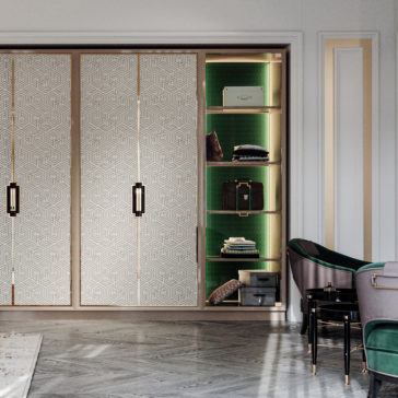 Large High End Integrated Wardrobe The Large High End Integrated Wardrobe features elaborate geometric patterned sliding doors, which, when partially open, reveal shelves set against a green textured background. Inside, neatly organized accessories and storage boxes are displayed. Complementing the wardrobe on the right are stylish chairs with dark green upholstery.
