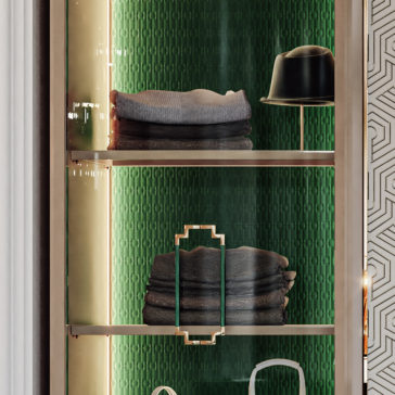 Large High End Integrated Wardrobe A Large High End Integrated Wardrobe featuring a glass cabinet with elegant gold framing, showcasing neatly folded clothing items and a black hat. The interior boasts a textured green background, while one side is adorned with a decorative geometric pattern, enhancing its sophisticated appearance.