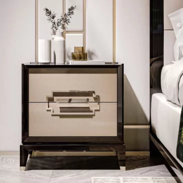 Luxury Two-Tone Lacquered Bedside Cabinet The Luxury Two-Tone Lacquered Bedside Cabinet, featuring two drawers with geometric handle designs, holds a vase with green foliage, stacked books, a gold sculpture, and a white decorative item. The setup is placed next to a bed adorned with white and grey bedding in a stylishly decorated room.