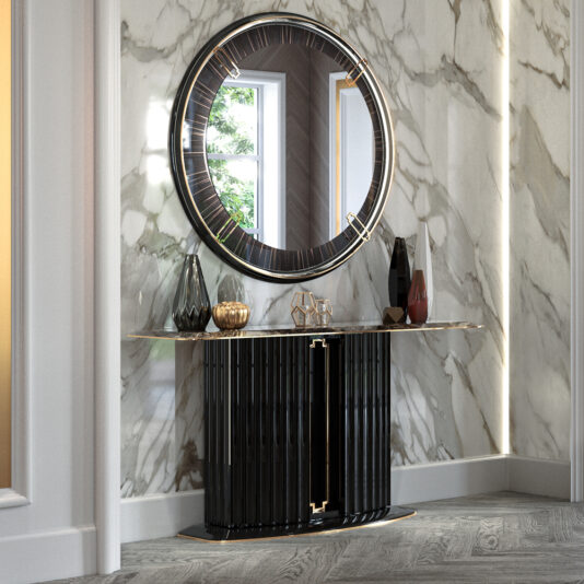 A luxurious marble hallway features a circular mirror with a black and gold frame above the Marble Art Deco Style Console Table, which showcases vertical slats and gold accents. The sleek black console holds decorative vases and a candle holder. The scene is illuminated by natural light from a nearby window.