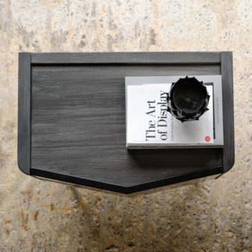 Modern Bedside Cabinet With Two Drawers A top-down view of a dark wooden table with a black vase and a hardcover book titled