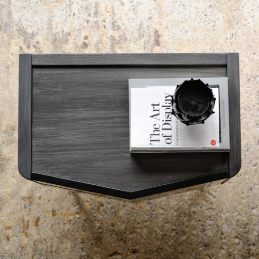 Modern Bedside Cabinet With Two Drawers A top-down view of a dark wooden table with a black vase and a hardcover book titled
