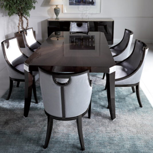 Modern Walnut Luxury Dining Chair A modern dining room featuring a rectangular dark wood table with a glossy finish, surrounded by six Modern Walnut Luxury Dining Chairs with black legs and light gray cushions on a light blue textured rug. A buffet with a lamp and glass decor is in the background against a white wall.