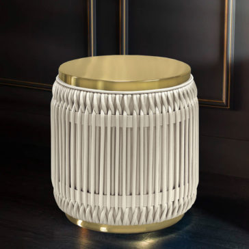 Round Satin Upholstered Side Table The Round Satin Upholstered Side Table gleams in the light with its small, elegant cylindrical design featuring a gold-colored top and bottom. The body is detailed with a white woven cord pattern, giving it a modern and chic look. Set against a dark background, this side table exudes sophisticated flair.