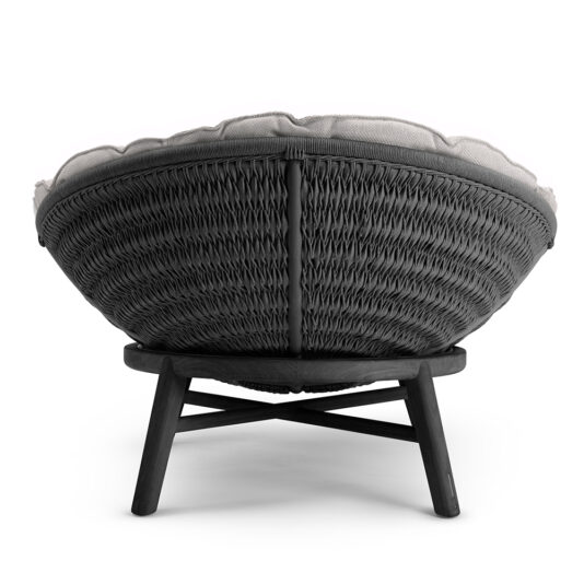 Contemporary Outdoor Woven Daybed The Contemporary Outdoor Woven Daybed features a circular, dark-material backrest with a rustic texture. It has a cushioned seat and rests on four angled wooden legs connected by crossbars, showcasing its curved design and inviting aesthetic from behind.