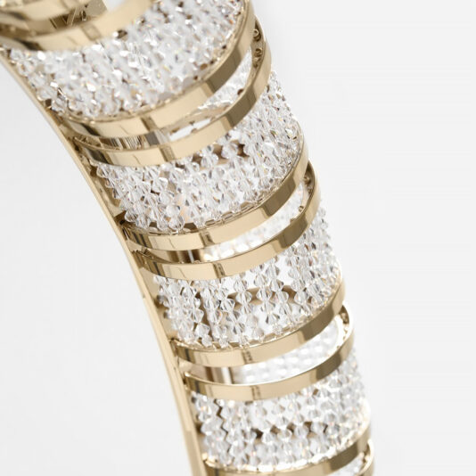 Contemporary Round Crystal Mirror Close-up of an ornate gold and crystal chandelier, showcasing a curved structure with numerous gold rings filled with intricately cut crystal beads. The chandelier sparkles elegantly against a light gray background, reminiscent of the sophisticated design seen in the Contemporary Round Crystal Mirror.