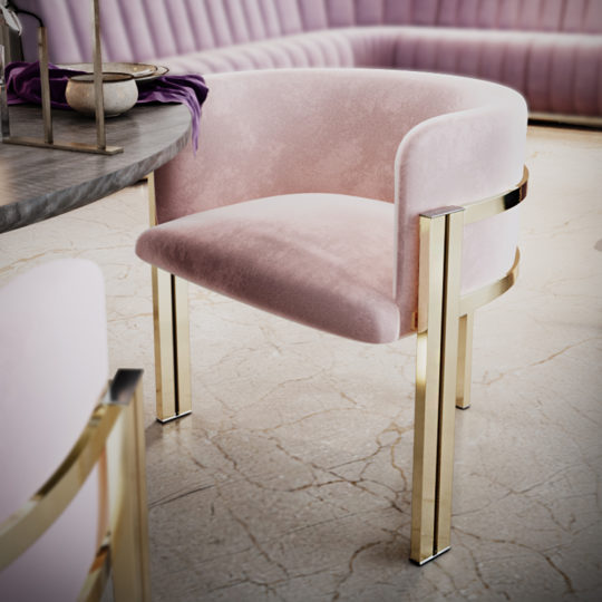 A stylish Round Modern Ribbed Veneer Dining Set is showcased with a plush pink chair featuring gold metal legs next to the modern, round table. The table's stone-like surface holds a small bowl and a folded purple cloth. In the background, a curved pink cushioned bench hugs the wall. The floor boasts a light-colored, cracked veneer finish.